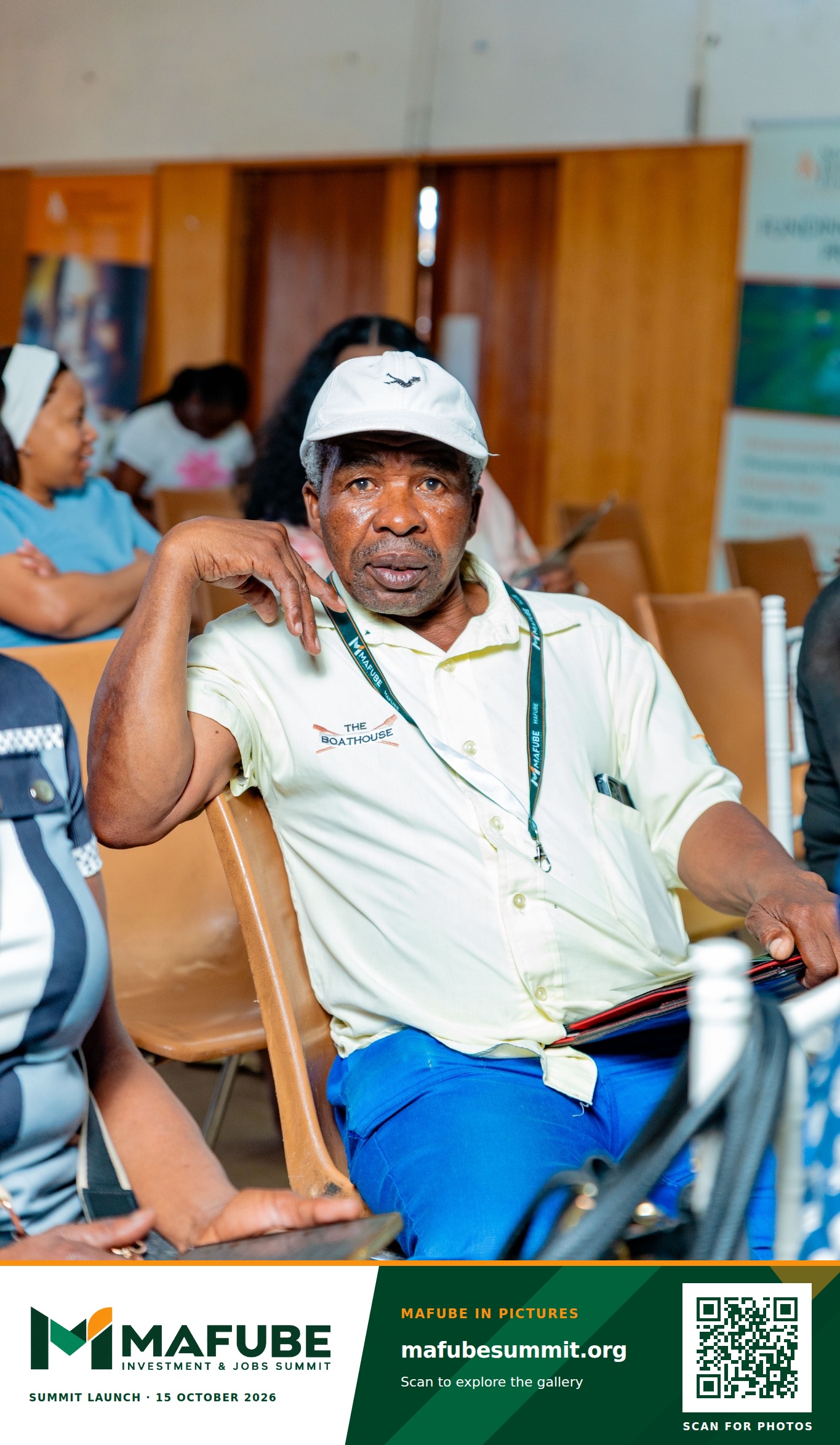 A participant listens during the summit launch, with the Mafube Investment & Jobs Summit photo footer