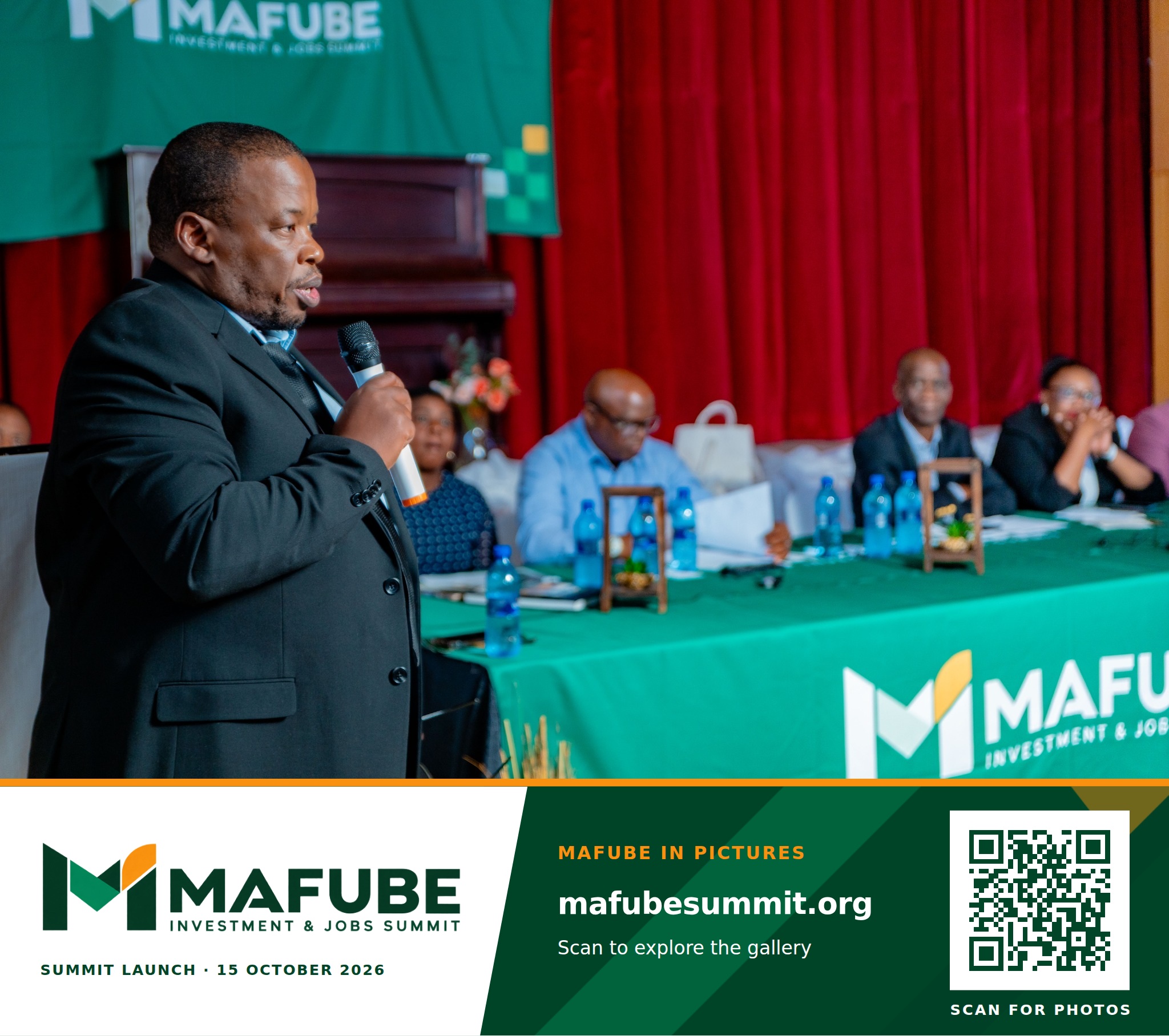 A participant speaks into a microphone in front of the head table, with the Mafube Investment & Jobs Summit photo footer