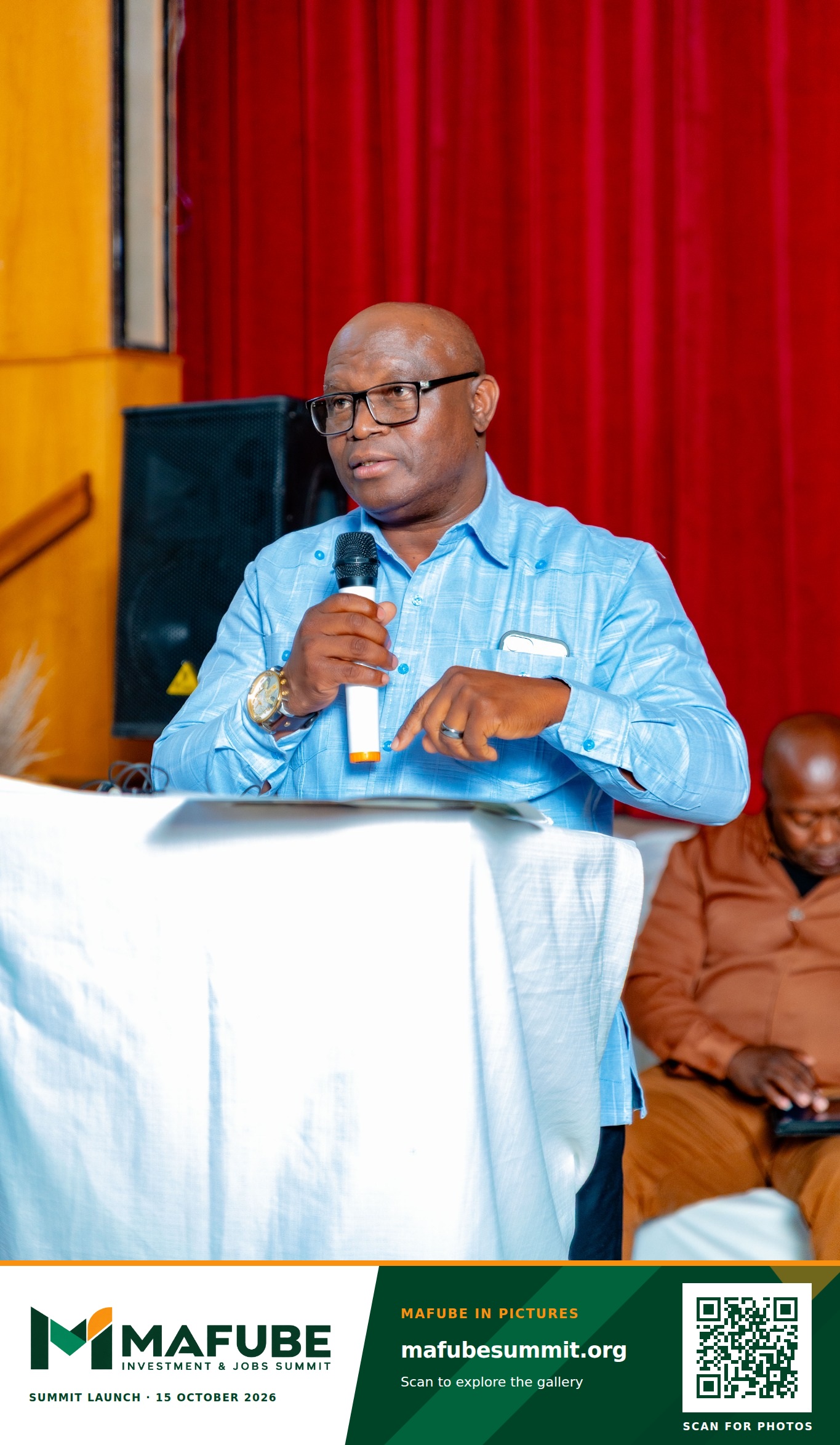 A speaker addresses the hall from the podium, with the Mafube Investment & Jobs Summit photo footer