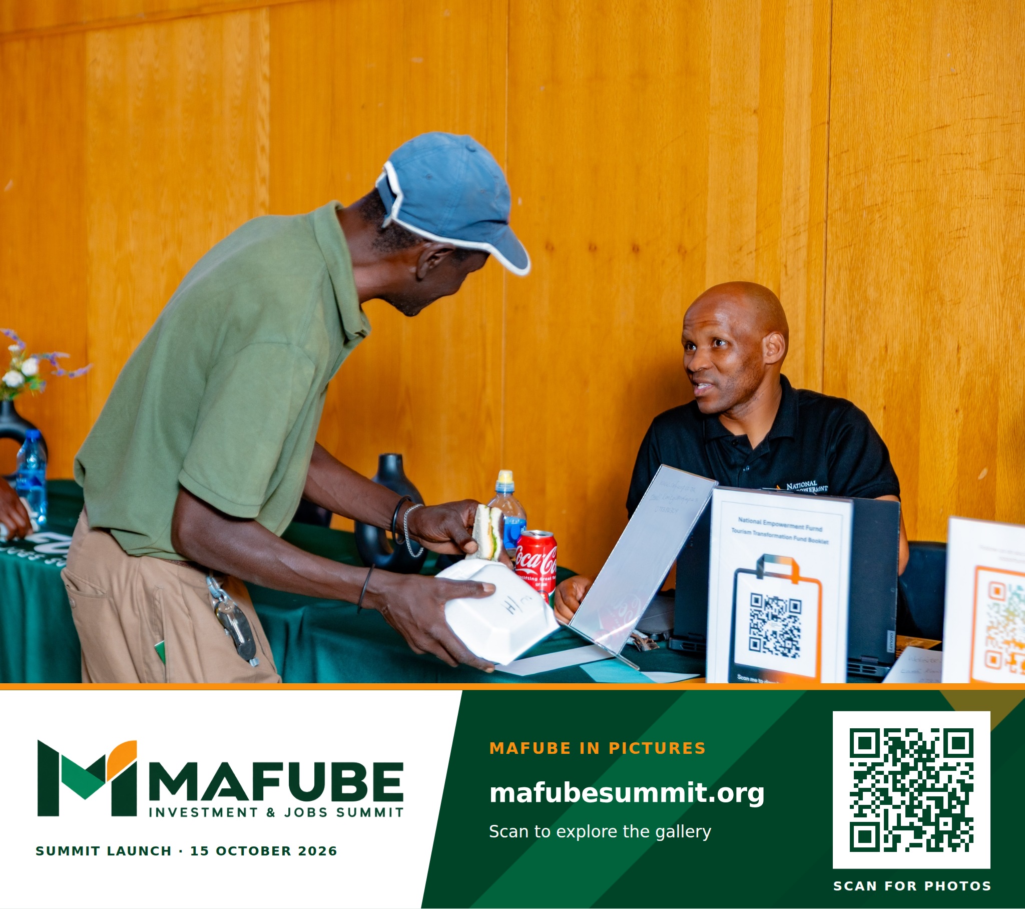 A participant collects material at a registration table, with the Mafube Investment & Jobs Summit photo footer